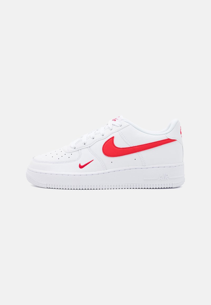 Baltas ādas sneakers ar zemu dizainu, ar sarkaniem Nike swooshem un akcentiem, perforētu pirkstu daļu un teksturētu gumijas zoli.
