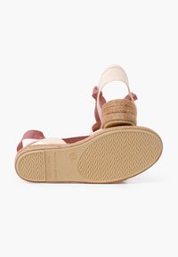 Sandales à talons compensés avec un talon en jute tissé et une semelle en caoutchouc. Tige en tissu beige clair avec une sangle de cheville rose, présentant un motif texturé.