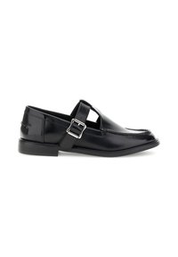 Mocasines de cuero negro con detalle de correa y hebilla, que cuentan con una textura suave, puntera redonda y suela de goma de perfil bajo.