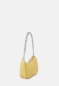 Żółta pikowana torebka na ramię z srebrnym łańcuszkiem i zamkiem błyskawicznym. Torebka ma zaokrąglony kształt i gładką, fakturowaną powierzchnię.