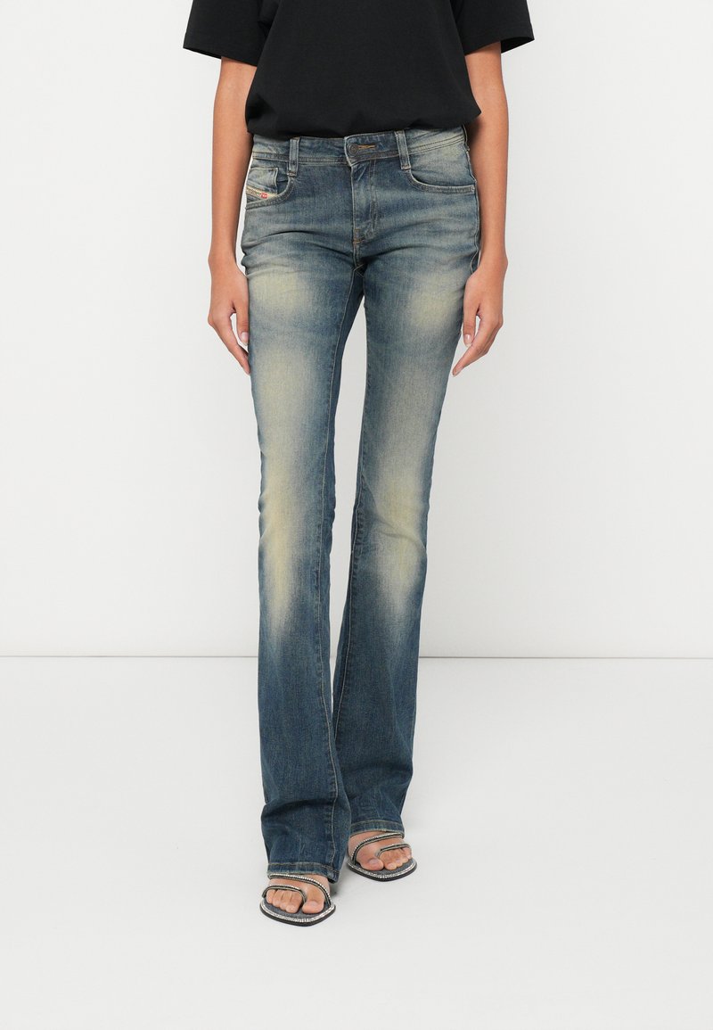 Blugi evazați din denim albastru mediu cu un finisaj decolorat, design cu cinci buzunare și găici pentru curea. Purtați cu un top negru și sandale elegante.