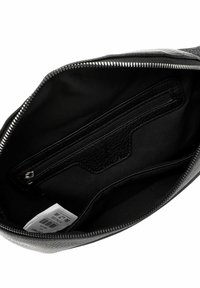 Interno di una borsa nera con zip, realizzato in tessuto liscio e opaco. Presenta una piccola tasca con zip e un'etichetta, con un accento in pelle texture contrapposta.