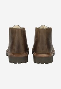 Bottes basses en cuir marron avec une semelle flexible, présentant une finition texturée, un bout arrondi et des détails de coutures sur les côtés.