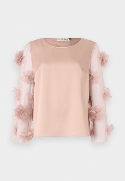 Top rosa chiaro con un corpo in satin uniforme. Le maniche trasparenti presentano fiori di stoffa sparsi, aggiungendo texture e dettaglio. Collo rotondo.