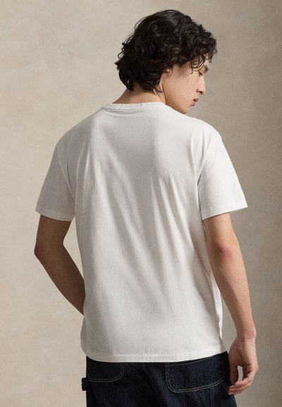 Λευκό βαμβακερό μπλουζάκι με κοντά μανίκια και στρογγυλή λαιμόκοψη, με ομαλή υφή και άνετη εφαρμογή. Η πίσω όψη δείχνει απλό σχέδιο.