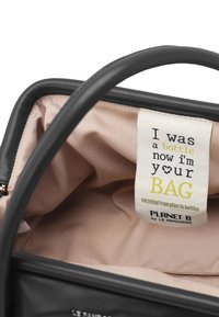 Borsa nera realizzata con materiali riciclati; presenta una texture liscia, una fodera in tessuto rosa e un'etichetta che indica la sua origine ecologica.