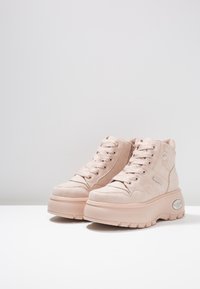 Rosa högskor av slät mocka med texturerade accenter, med runda snörningar, en tjock plattformssula och varumärkesdetaljer.