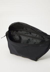 Borsa in tessuto nero con chiusura a zip, caratterizzata da una superficie liscia, un motivo a righe orizzontali e una piccola tasca interna con zip.