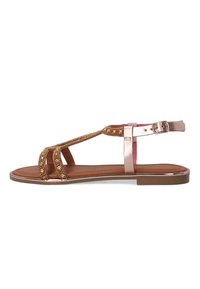 Braune flache Sandalen mit metallischen Akzenten, ausgestattet mit einem T-Strap-Design, das mit kleinen Perlen verziert ist, und einer Schnallenverschluss am Knöchel.