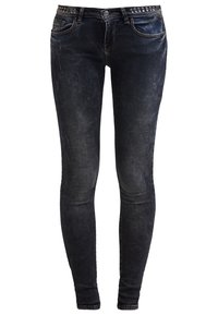 Vaqueros pitillo de lavado oscuro con sutiles desgastes y una cinturilla con tachuelas, que cuentan con bolsillos delanteros y traseros y cierre de botón.