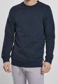 Felpa blu navy in misto cotone, modello girocollo con polsini e orlo a coste, caratterizzata da una texture liscia e una silhouette aderente.