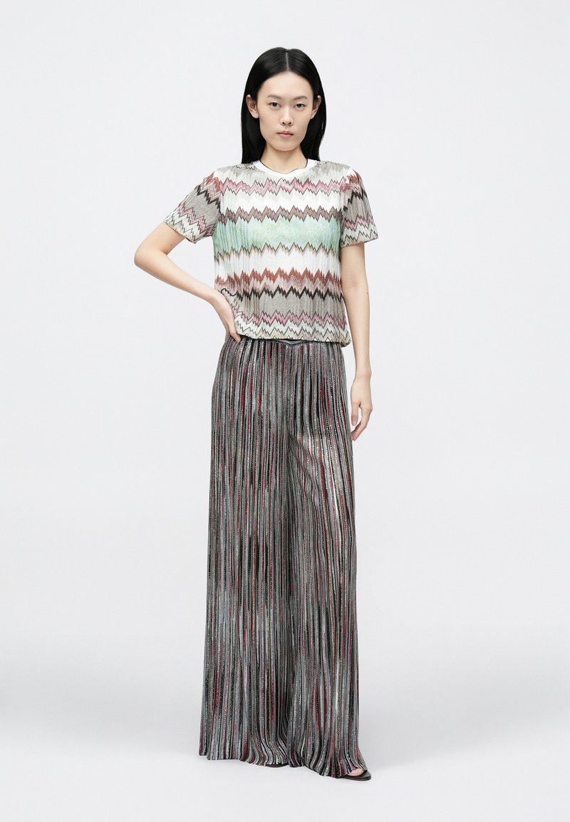 Top tejido con un patrón de zigzag en colores pastel, combinado con pantalones anchos plisados metálicos, creando un look texturizado y en capas.