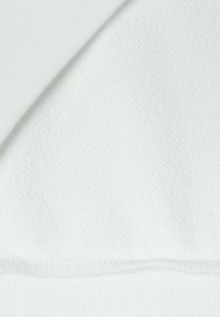 Tessuto in pile bianco con una superficie testurizzata, caratterizzato da sezioni lisce e rigate, con un aspetto uniforme e morbido in tutto.