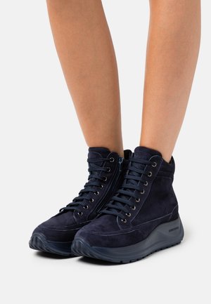 Botas de tobillo de ante azul marino con cordones prominentes, cremallera lateral, acabado texturizado y suela de goma deportiva.