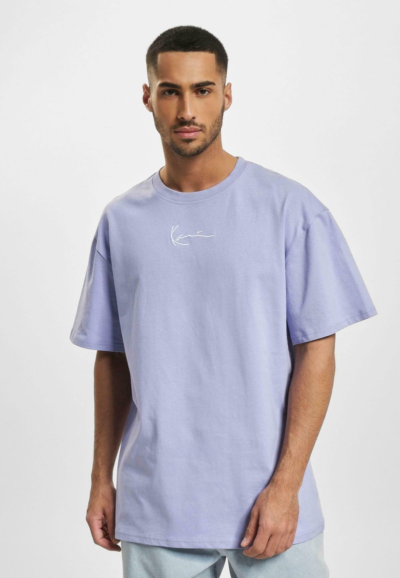 Lavendelfarvet bomulds t-shirt med løs pasform, korte ærmer og et lille hvidt logo på brystet. Glat struktur og minimalistisk design.
