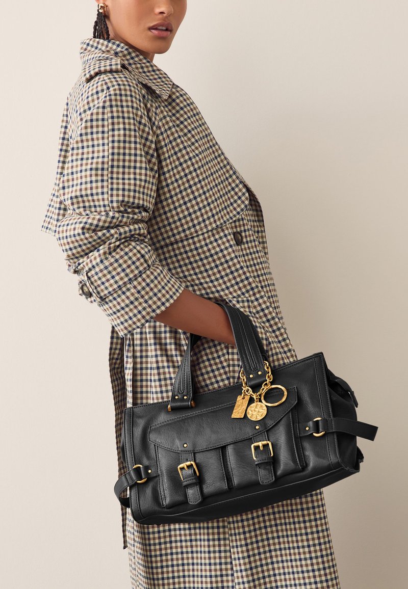 Melnas ādas soma ar zelta detaļām, kurai ir vairāki kabatas priekšpusē, gluda tekstūra un divi rokturi ērtai nēsāšanai.