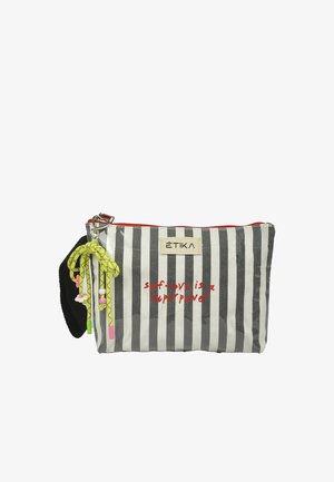 Pequeño estuche rectangular con rayas blancas y negras, cremallera roja, cordón amarillo con cuentas, y texto en rojo que dice "el amor propio es un superpoder".