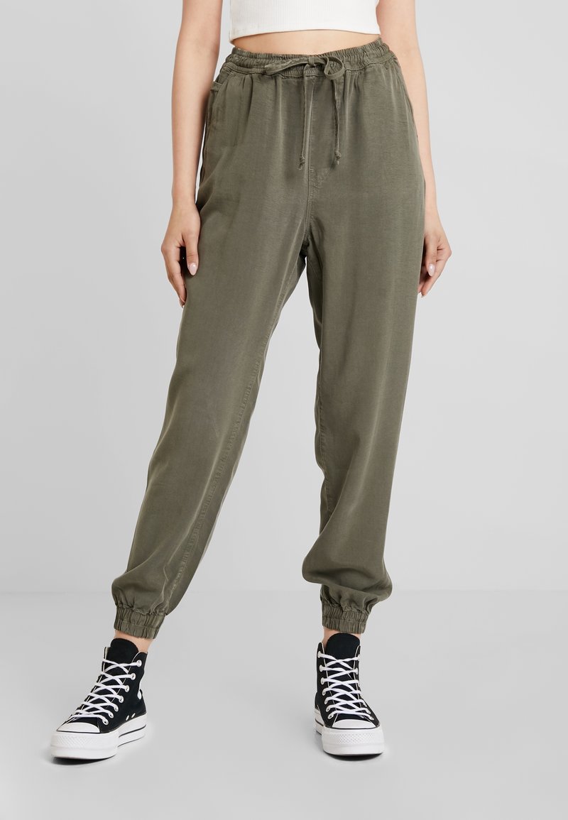 Olivgrön, lätta joggingsbyxor med elastisk midja och samlade manschetter. Matchas med svarta högskaftade sneakers.