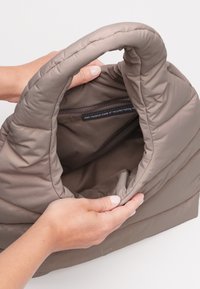 Khaki torba wykonana z recyklingowych sieci rybackich, z wyściełanym designem i przestronnym, gładkim wnętrzem z zasuwaną kieszenią.