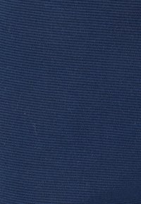 Marineblauwe ribstof met een gestructureerd oppervlak, gelijkmatig geweven met fijne lijnen, geschikt voor kleding en zachte meubels.