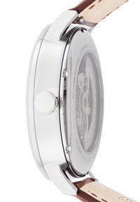 Edelstahl-Uhr mit einem transparenten Gehäuseboden, braunem Lederarmband und einer strukturierten Krone. Elegantes Design mit minimalistischen Merkmalen.