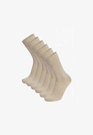 Fünf beige gerippte Knöchelsocken, versetzt in einer Reihe auf weißem Hintergrund.