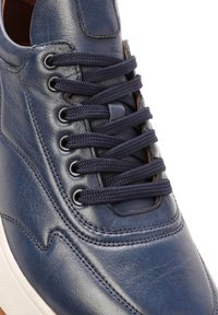 Marineblauwe leren sneaker met ronde neus, dikke veters, metalen oogjes en een gestructureerd oppervlak met subtiele stiksel details. Witte rubberen zool.