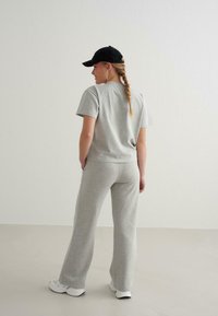 Grå bomulds t-shirt og matchende brede sweatpants, accessoriseret med en sort kasket. Outfittet har en afslappet pasform og blød tekstur.
