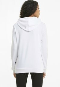 Hanorac alb cu glugă, cu o croială lejeră, având o textură moale și manșete și tiv côtelat. Design minimalist, simplu, fără modele.