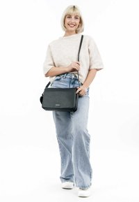 Black leather crossbody bag with a textured finish, rectangular shape, and a long strap. Features a magnetic closure and subtle branding.