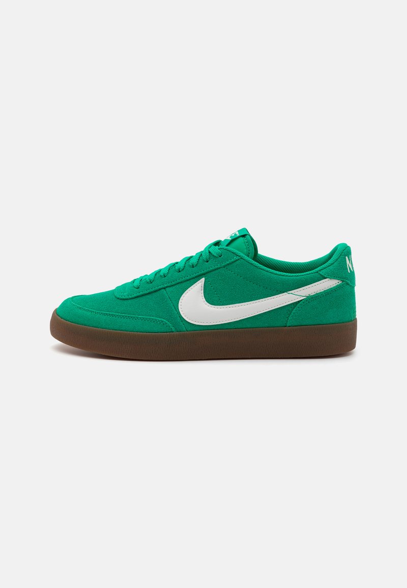 Zaļie zamšādas sporta apavi ar baltu Nike Swoosh, teksturēts augšdaļa, auklīšu dizains un gumijas zole. Gludas akcenti un noapaļota forma.