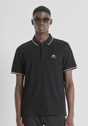 Zwarte poloshirt met witte kraag en accenten op de mouwen, gemaakt van katoen, met een knoopsluiting van twee knopen en een logo op de linkerborst.