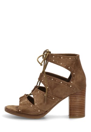 Sandalia de tacón alto en ante marrón con punta abierta, cordones en la parte delantera, laterales recortados, tachuelas plateadas y tacón de bloque apilado.