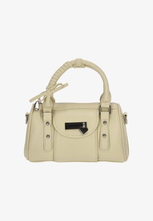 Bolso de mano color crema hecho de material sintético, con un asa superior redondeada, cierre de cremallera, lazo decorativo y un pequeño charm en forma de corazón.