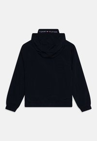 Black hooded jacket with elastic cuffs and waistband, featuring "Tommy Hilfiger" logo on the back of the collar.