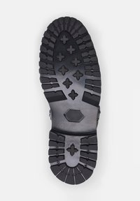 Sole in gomma nera con un battistrada robusto, caratterizzato da forme incrociate e esagonali per una migliore aderenza e trazione.