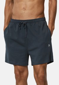 Navy blue, cotton blend shorts with an elastic waistband, drawstring, and side pockets. Features an embroidered logo on the lower left leg.