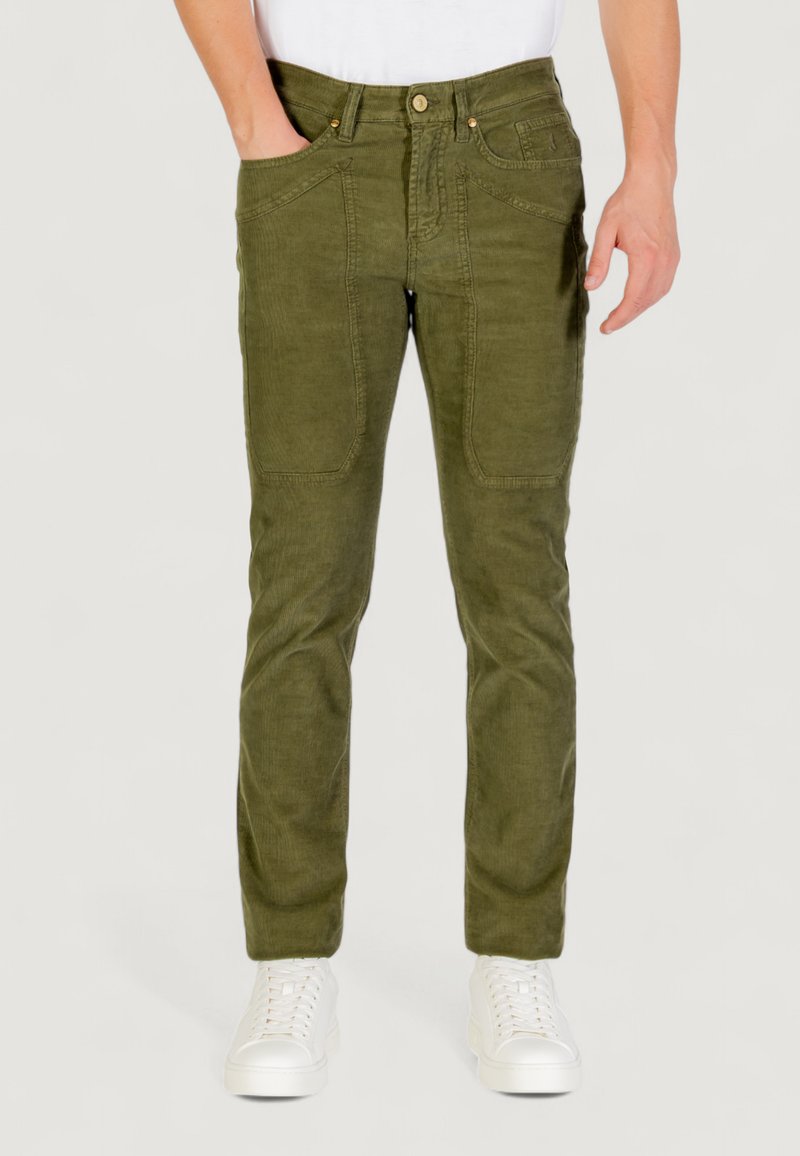 Pantaloni di velluto a coste verde oliva con fit slim, dotati di tasche frontali, chiusura con bottone e tessuto testurizzato. Sneakers bianche indossate.