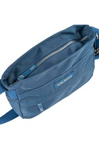 Bolso de tela azul para el hombro con forma rectangular, que cuenta con cierre de cremallera, bolsillo frontal y una etiqueta de marca. Textura lisa y correa ajustable.