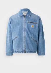 Lichtblauwe denim jas met een kraag, voorsluiting met rits en twee zijzakken. Bevat een kleine borstzak en een logo patch.