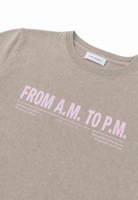 Μπεζ T-shirt με στρογγυλή λαιμόκοψη και ροζ κείμενο "FROM A.M. TO P.M." και μικρότερες λευκές φράσεις για τη ροή και το αίσθημα του σπιτιού, με σήμανση OH APRIL.