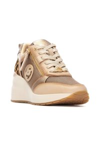 Zapatilla deportiva beige con acentos metálicos dorados, paneles de malla y suela de cuña elevada. Presenta un zipper lateral y detalle de estampado de leopardo.