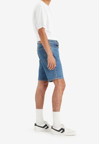 Ljusblå denimshorts med rak passform, fem fickor och sydda detaljer. Bärs med en vit t-shirt och vita strumpor.