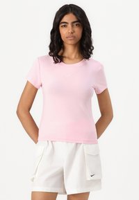 Tricou roz cu mânecă scurtă, având un guler rotund și un mic logo alb Nike pe piept, fabricat dintr-un material moale și neted.