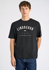 Camiseta de algodón negra con mangas cortas y cuello redondo, que presenta el texto blanco "Lindbergh 1927 Copenhague" y un gráfico de montañas.