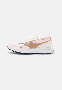 Nike-sneakers med en ljusrosa ovandel, strukturerade överlägg, orangea detaljer och en vit mellansula med en svart gummisula.