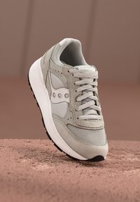 Light grey sneaker with mesh and suede materials, featuring a lace-up design, logo accents, and a white midsole with a black outsole.