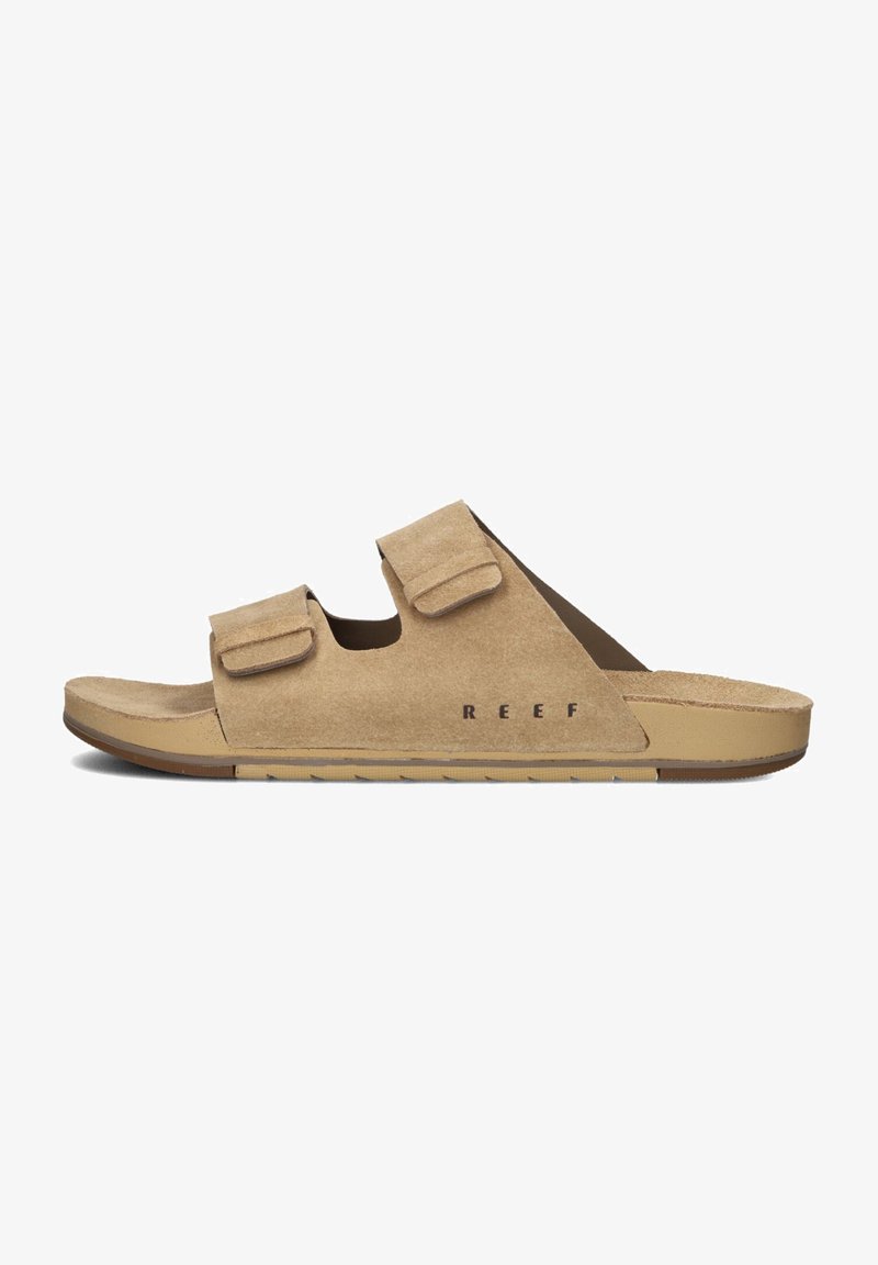 Sandalias de ante en beige claro con dos correas de velcro ajustables. Cuenta con una plantilla contorneada y una suela de goma para mayor agarre. Logo impreso en el lateral.