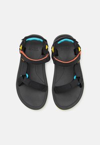 Sandalias negras con correas ajustables; detalles en azul brillante, amarillo y naranja; suela texturizada y flexible.