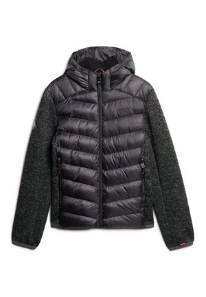 Veste noire rembourrée avec fermeture éclair sur le devant, capuche et manches gris qui ressemblent à de la laine. Dotée de coutures diagonales et d'un logo sur la poitrine.